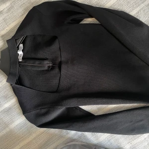 Svart tröja med dragkedja från Zara - Snygg svart tröja från Zara med dragkedja framtill. Perfekt för en stilren look. Tröjan har långa ärmar och en enkel design som passar till många tillfällen.