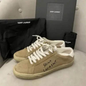 Beige sneakers från Saint Laurent - Snygga beige sneakers från Saint Laurent i modellen SL/06. Hör av er vid frågor elller fler bilder. Priset är diskuterbart.