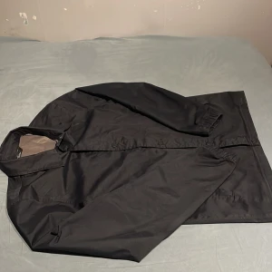 Svart windbreaker/overshirt från The North Face - Säljer en stilren svart jacka från The North Face. Jackan har långa ärmar och knappar framtill. Perfekt för en casual look. Jackan är vatten tät och vindtät!!!