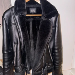Svart skinnjacka från ONLY - Snygg svart skinnjacka från ONLY med mjukt foder och krage i pälsimitation. Jackan har dragkedja och stilrena detaljer. Perfekt för kyligare dagar.