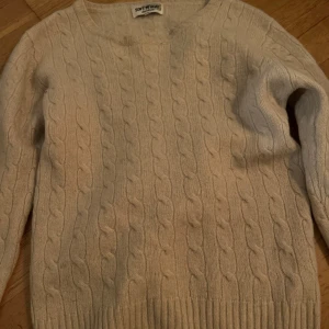 Beige stickad tröja från Soft Goat - Mysig beige stickad tröja från Soft Goat med klassiskt flätmönster. Perfekt för kyliga dagar med sin varma och bekväma design. Tröjan är kashmir men lite små utvättad.. Pris kan diskuteras!!