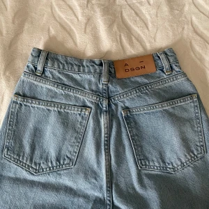 Ljusblå jeans från A-DSGN - Säljer ett par snygga ljusblå jeans från A-DSGN i storlek XXS. De är tillverkade av 100% bomull och har en klassisk design med fem fickor och knappgylf. Perfekta för en avslappnad vardagslook! Nypris 700kr