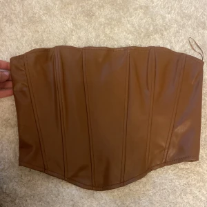 Korsett - Brun korsettopp i läderimitation. Storlek XS men skulle kunna passa en mindre S också, endast testad så nyskick. Vid fler bilder eller frågor är det bara att skriva, tar emot prisförslag❤️