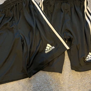 Svarta shorts från Adidas - Säljer ett par svarta shorts Adidas.  De är i ett sportigt och bekvämt material, perfekt för träning eller vardagsbruk. Använda men är i bra skick. 2 för 75, 1 för 45