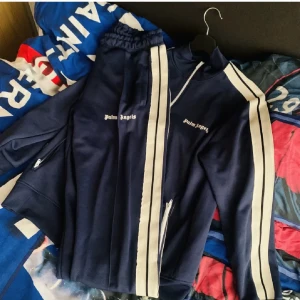 Palm angels tracksuit - säljer en fin Palm angels tracksuit i bra skick. Inga fel alls använd ett par ggr lite stor på mig. Så jag säljer pga den hänger bara i garderoben. vill byta ut den mot något annat,eller en lila tracksuit i M rätt nyans.Hör av er,köpte den på pliq