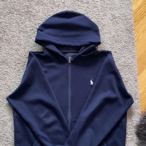 Mörkblå hoodie från Ralph Lauren - Säljer en snygg och stilren mörkblå zip hoodie från Ralph Lauren. Den är i perfekt skick och Storlek M. Skriv vid frågor och funderingar!