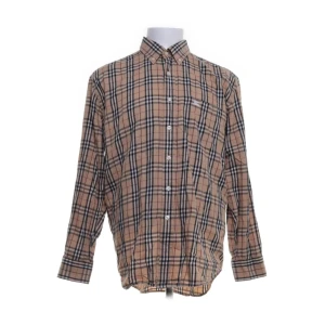 burrberry skjorta med knappar - Snygg rutig skjorta i beige och svart med klassisk krage och knappar framtill. Perfekt för en stilren look.