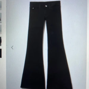 Cheap Monday svarta  - Snygga svarta bootcut byxor med låg midja. Perfekta för en stilren look. Byxorna har en klassisk design med dragkedja och knappar framtill.