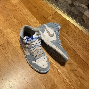 Nike Air Jordans i blått och vitt - Snygga Nike Air Jordans i en fräsch kombination av blått och vitt. Skorna har en klassisk hög design med snörning och perforerade detaljer på tån för extra ventilation. Perfekta för både stil och komfort.