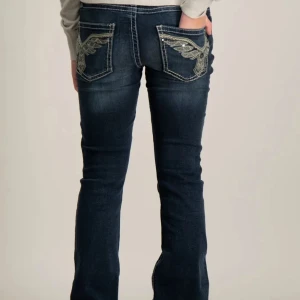 Lowaist Mörkblå bootcut jeans😍 - Snygga mörkblå jeans med broderade detaljer på bakfickorna. De har en bootcut-stil och kontrasterande sömmar som ger en cool look. Perfekta för en avslappnad stil med en touch av detaljer, säljer dom pågrund av för mkt jeans. Därav inte kommer till användning. Köpta för 400 och säljer för 260. Använda fåtal gånger 