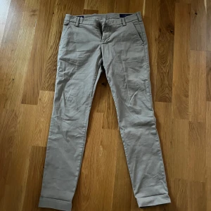 Beige chinos från Entre Amis -  beige chinos från Entre Amis med dragkedja och knappstängning. De har en klassisk design med bälteshällor och fickor både fram och bak. Perfekta för en stilren look.