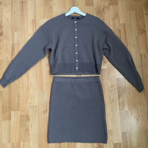 Brun kofta och kjol set från Gina Tricot  - Snyggt set med en brun kofta och matchande kjol. Koftan har långa ärmar och knappar framtill, medan kjolen är enkel och figurnära. Endast använda vid ett tillfälle! 