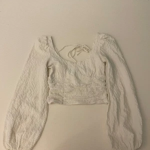 Vit blus med knytband - Snygg vit blus med långa ärmar och knytband i ryggen. Har nå små märke när jag fick den men orkade inte byta, kan skicka bild om önskat. Finns att hämta i Härnösand också.