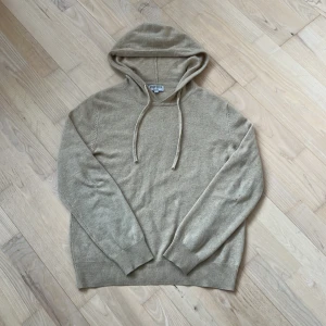 Cashmire från ROVOIR - Säljer en riktigt eftertraktad beige hoodie från ROVOIR i storlek S. Tröjan är tillverkad i cashmire och har en klassisk huva med dragsko. Jätte mjuk och riktigt snygg! Obs ett litet hål i armbågen som lätt går att sy ihop och det syns ej vid användning annars topp skick!