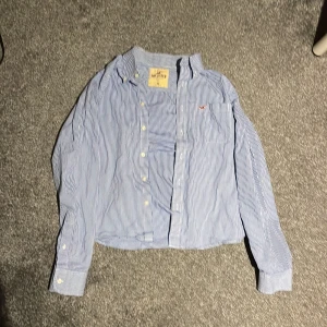 Blårutig skjorta från Hollister - Snygg blårutig skjorta från Hollister i storlek XL. Skjortan har långa ärmar och knappar framtill. Perfekt för en avslappnad stil med en klassisk touch. Skjortan är i storlek xl men sitter som M/L