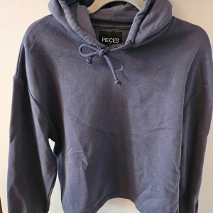 Blå hoodie från Pieces - Säljer en snygg blå hoodie från Pieces. Mycket mjukt mysigt tyg på insidan. Den har en justerbar huva med knytband och långa ärmar. Perfekt för en avslappnad stil. Ej använd.