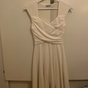 Vit klänning från Chiara Forthi - Elegant vit klänning från Chiara Forthi med draperad överdel och breda axelband. Perfekt för en stilren look. Klänningen har en vacker fallande kjol och är tillverkad i ett mjukt material. I ett mycket bra skick!