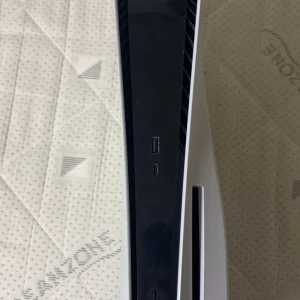 PlayStation 5 med FIFA 23 och FC 24 spel - Säljer en PlayStation 5 med två spel: FIFA 23 och FC 24. Konsolen är vit med en elegant design och inkluderar en handkontroll, laddningskabel och stativ. Perfekt för spelentusiaster som vill uppleva nästa generations grafik och spelupplevelse.