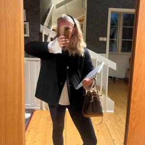 Svart kappa med knappar - Snygg svart kappa med knappar framtill. Perfekt för höst och vinter. Klassisk design som passar till många olika stilar.Jag har sytt upp den själv så den blir kortare 