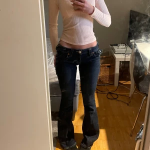 True Religion Joey Low Rise Flare Jeans - Säljer ett par snygga True Religion jeans i modellen Joey Low Rise Flare köpta från Nelly De är i ett bra skick och i storlek 24.