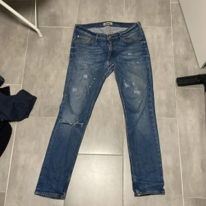 Blå jeans från Acne - Säljer ett par snygga blå jeans från Acne i bra skick. Dom har snygga slitningar. Storleken passar 30-32. Dom har en liten fläck vid högra knät men det påverkar inget tycker jag. Skriv vid fundering