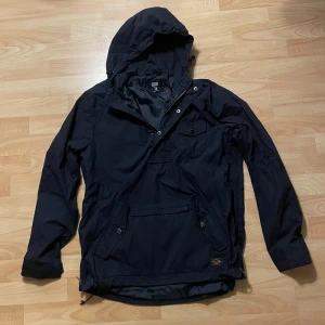 Svart vindjacka med huva - Säljer en svart vindjacka från FSBN i storlek S. Den har en praktisk huva och en stor ficka framtill. Perfekt för höst samt som jacka till skidåkning. Den är i mycket bra skick. Skriv för fler bilder eller andra funderingar. 