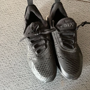 Nike air Max 270 - Svarta Nike sneakers - Säljer ett par svarta Nike sneakers i bra skick. De har en snygg och modern design med snörning och en bekväm sula. Perfekta för både träning och vardagsbruk. Skorna har en luftig ovandel och en stabil häl för extra komfort.