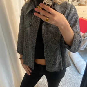 Grå kappa med knappar - Säljer en snygg grå kappa med trekvartslånga ärmar. Den har en fläck på vänstra ärmen💕