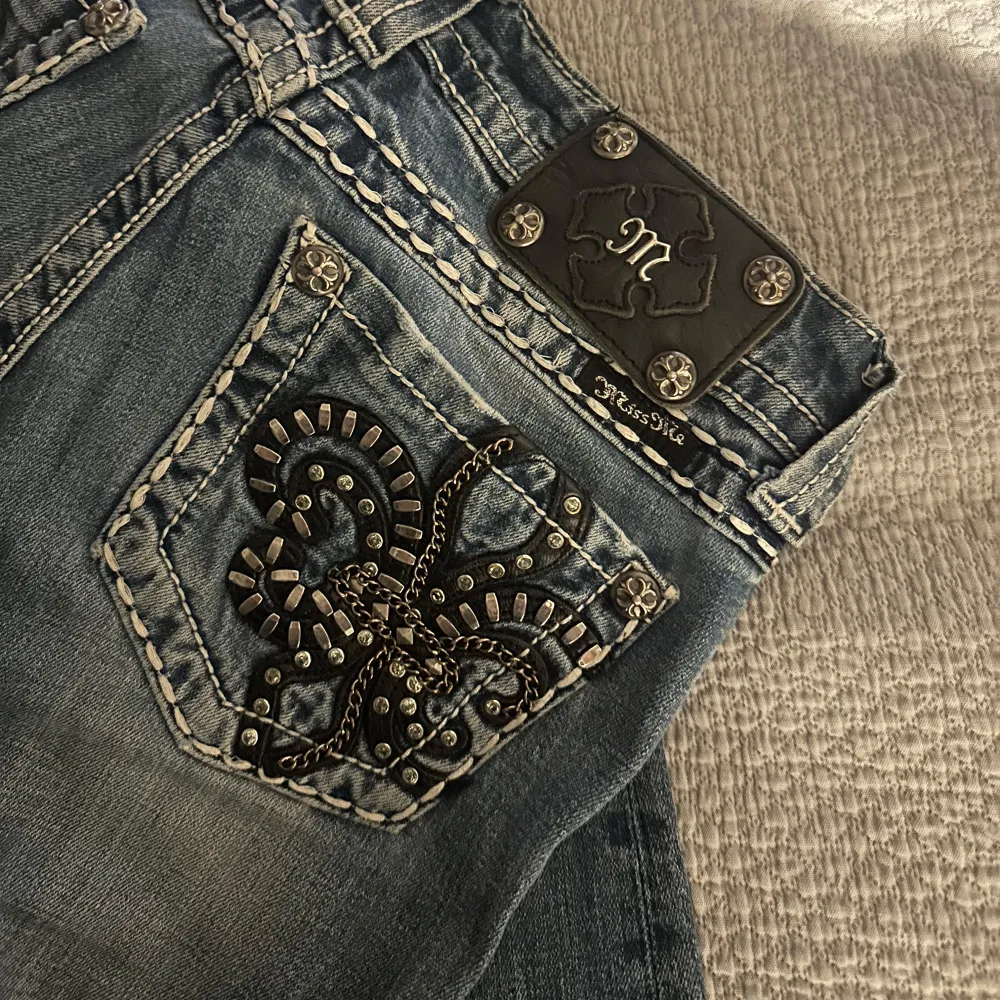 Snygga blå jeans från Miss Me i storlek 26. De har en unik broderad ficka med nitar och ett coolt mönster. Jeansen är i bra skick och har en bootcut-stil. Perfekta för både vardag och fest! Knappt använda . Jeans & Byxor.