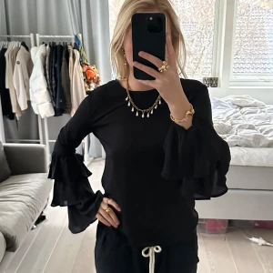 Svart blus med volangärmar XS - Säljer en elegant svart blus med långa volangärmar. Perfekt för både vardag och fest! Blusen har en normal passform och är gjord i ett mjukt material som känns skönt mot huden. Den är stilren och lätt att matcha med olika accessoarer. Passar perfekt till höst och vår. Märket är IVYREVEL och storleken är XS, nypris: 479. Den saknar en knapp i nacken där man knäpper den men det är enkelt att sy dit en ny, därav lågt pris
