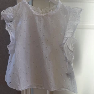 Vit blus från H&M - Säljer en söt vit blus från H&M i storlek M. Den har ett fint broderat blommönster och volangdetaljer vid ärmarna🌸
