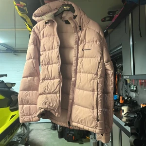 Ljusrosa dunjacka från Peak Performance - Säljer en superfin ljusrosa dunjacka från Peak Performance i storlek S. Jackan är perfekt för kalla dagar med sin pufferstil och långa ärmar. Den har en praktisk dragkedja och en mysig huva. Perfekt för både höst och vinter! 💖