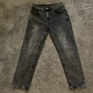 Grå jeansbyxor - Säljer ett par grå jeansbyxor i bra skick. De har en klassisk femficksdesign med knapp och dragkedja framtill. Byxorna har en straight passform och är perfekta för både vardag och fest. De är tillverkade i slitstarkt denim och har en snygg tvättad look. De är helt nya, aldrig använda.