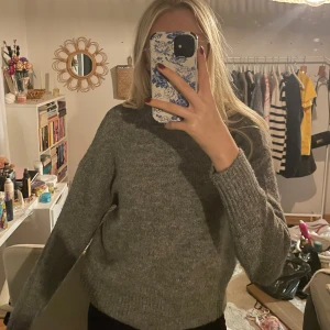 Grå stickad tröja - Säljer en mysig grå stickad tröja i mycket bra skick. Perfekt för höst och vinter med sin varma och bekväma passform. Tröjan har långa ärmar och ribbade muddar som ger en klassisk look. Perfekt för att hålla sig varm och stilren under kyliga dagar.