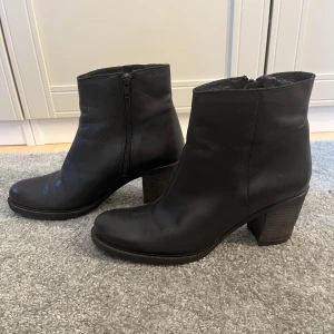 Svarta skinnstövletter med klack - Klassiska snygga Stövletter/boots i äkta skin från Bianco i storlek 40. Använda och lite slitna på klacken. Men skinnet på skon är i gott skick 😊💕.