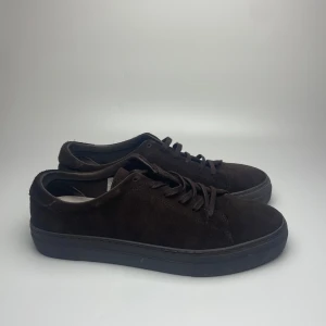 Bruna mocka sneakers - Säljer ett par snygga bruna sneakers i mocka. De har en stilren design med snörning och en bekväm sula. Perfekta för både vardag och fest! Skorna är i bra skick och redo för nya äventyr. 43 passar 44