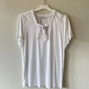 Vit blus - Vit blus med rosett från Rosebud, storlek M. Väldigt mjukt tyg och nästan aldrig använd!