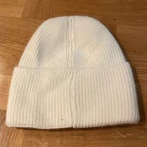 Säljer en superfin vit stickad mössa från ALVII beanie.  är ribbad och perfekt för kalla dagar. Mössan är i ny skick och passar perfekt till både höst och vinter. Den är mjuk och bekväm, och håller dig varm och stilren hela säsongen. Nypris 399:-