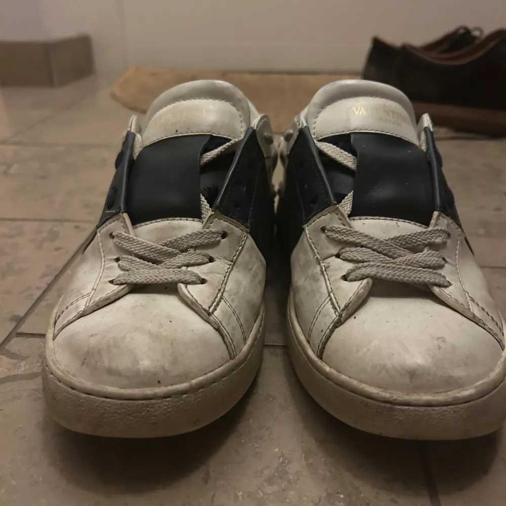 Säljer ett par Valentino sneakers i vitt med blå detaljer. Skorna har snörning och är i acceptabelt skick men ganska smutsiga och dem har färgats av sig av några jeans så dem är lite blåa innan för skorna . Skor.