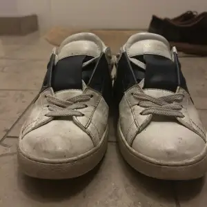 Säljer ett par Valentino sneakers i vitt med blå detaljer. Skorna har snörning och är i acceptabelt skick men ganska smutsiga och dem har färgats av sig av några jeans så dem är lite blåa innan för skorna 