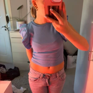 Blå ribbad topp från Zara - Säljer en superfin blå ribbad topp från Zara. Den är croppad och har volangdetaljer på ärmarna. Perfekt för sommardagar eller en avslappnad fest. Toppen är i mycket bra skick och passar perfekt till jeans eller kjol.