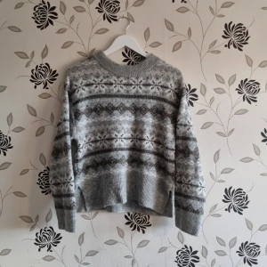 Grå mönstrad tjocktröja från H&M i Strl: XS - Säljer en supermysig grå tröja från H&M i storlek XS. Den har ett snyggt mönster i olika grå nyanser och är perfekt för kyliga dagar. Tröjan är tillverkad i en mjuk blandning av akryl, polyester och ull, vilket gör den både varm och bekväm. Passar perfekt till både vardag och mysiga hemmakvällar.