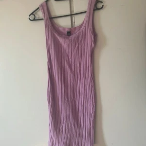 Ljuslila ribbad klänning - Säljer en superfin ljuslila ribbad klänning i tight passform. Perfekt för sommardagar eller en avslappnad vårlook. Klänningen är ärmlös och har en enkel design som gör den lätt att styla med olika accessoarer. Ett måste i garderoben för en chic och bekväm stil!