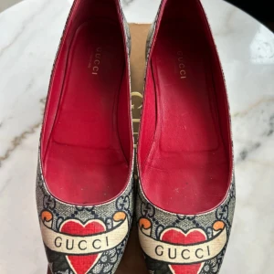 Gucci loafers med hjärtmönster - Säljer ett par snygga Gucci loafers i mycket bra skick. De har ett unikt hjärtmönster med Gucci-logga och röd insida. Perfekta för att ge din outfit en lyxig touch. Passar både till vardags och fest. Köpte dem för 4600kr, använt dem par gånger