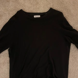 Svart tröja från Jack & Jones - Säljer en stilren svart tröja från Jack & Jones. Perfekt för både vardag och fest. Tröjan har en klassisk design med rund hals och långa ärmar. Passar bra till jeans eller chinos för en avslappnad look. Skick 9/10
