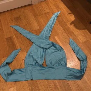 Turkos fest topp från Gina Tricot - Säljer en snygg turkos fest topp från Gina Tricot i storlek S. I nått typ av silkes formatDen har en enkel och stilren design med knytband för justerbar passform. Finns en lite fläck på ena axelbandet, men inget som förstör helheten