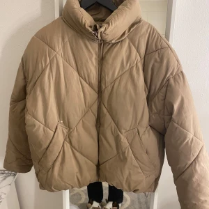 Beige quiltad pufferjacka från /STAY - Säljer en beige quiltad pufferjacka från /STAY i storlek XS. Jackan har en dragkedja framtill och är perfekt för höst och vinter. Den är i acceptabelt skick med en liten reva vid fickan. Supermysig och varm för kyliga dagar!