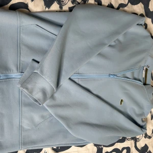 Lacoste och Polo Hoodie - Säljer två snygga ljusblå hoodie från Lacoste och Polo i mycket bra skick för att jag bytte min stil. Den har en dragkedja framtill och den är varmt. Perfekt för både vår och höst, och den är supermjuk och bekväm. Passar perfekt för en casual look! 💙Skriv för mer info! 