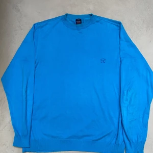 Blå stickad Paul & Shark tröja - Säljer en riktigt snygg och extremt skön tröja från Paul & Shark. Den är i storlek L. Tröjan har extremt skönt material och man känner att det är av hög kvalité. Nypris på tröjan ligger runt 3000kr. Tröjan är väldigt ovanlig då alla deras kläder är limiterade. Tveka inte på att höra av er vid frågor eller funderingar.