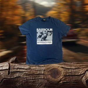 Blå t-shirt från Barbour International - Säljer en blå t-shirt från Barbour International med ett coolt tryck av motorcyklar på framsidan. Perfekt för en avslappnad stil. T-shirten har korta ärmar och en rund halsringning. Nypris 1000kr. Mitt pris 450kr. Har såklart kvittot på den och Season man bag från att jag köpte den⚡️